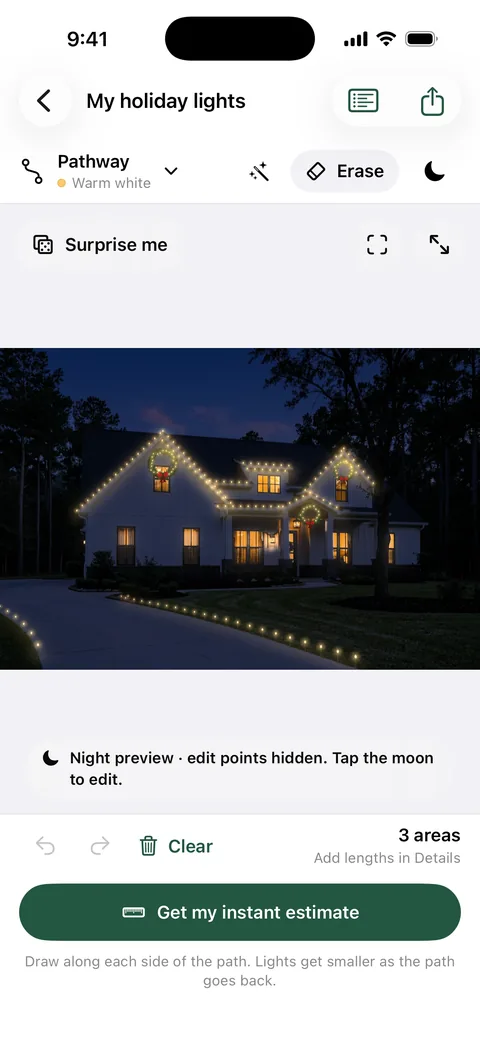 The farmhouse in Everglow’s Night preview, with warm white lights on the roofline, three wreaths and lights along the driveway.